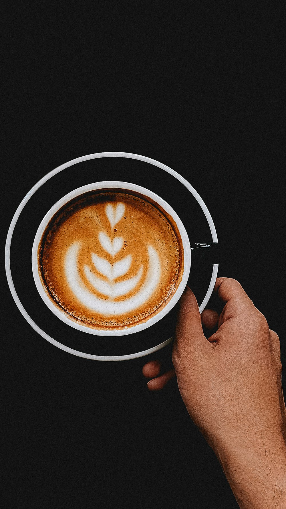 person holding white ceramic mug with brown liquid