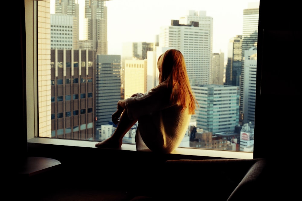 woman sitting on window during daytime