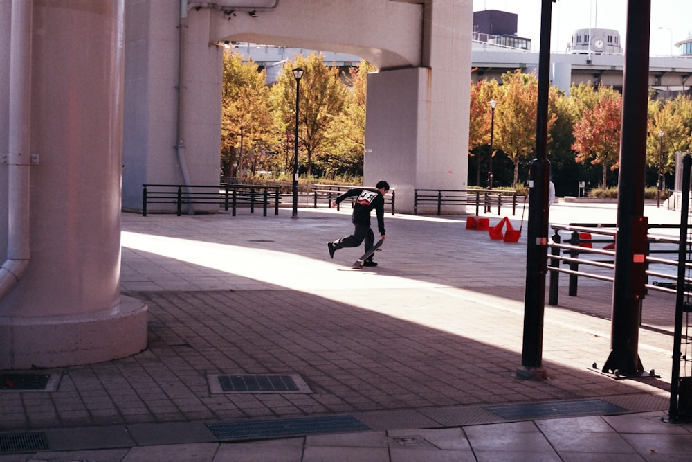 man in black jacket and black pants walking on sidewalk during daytime