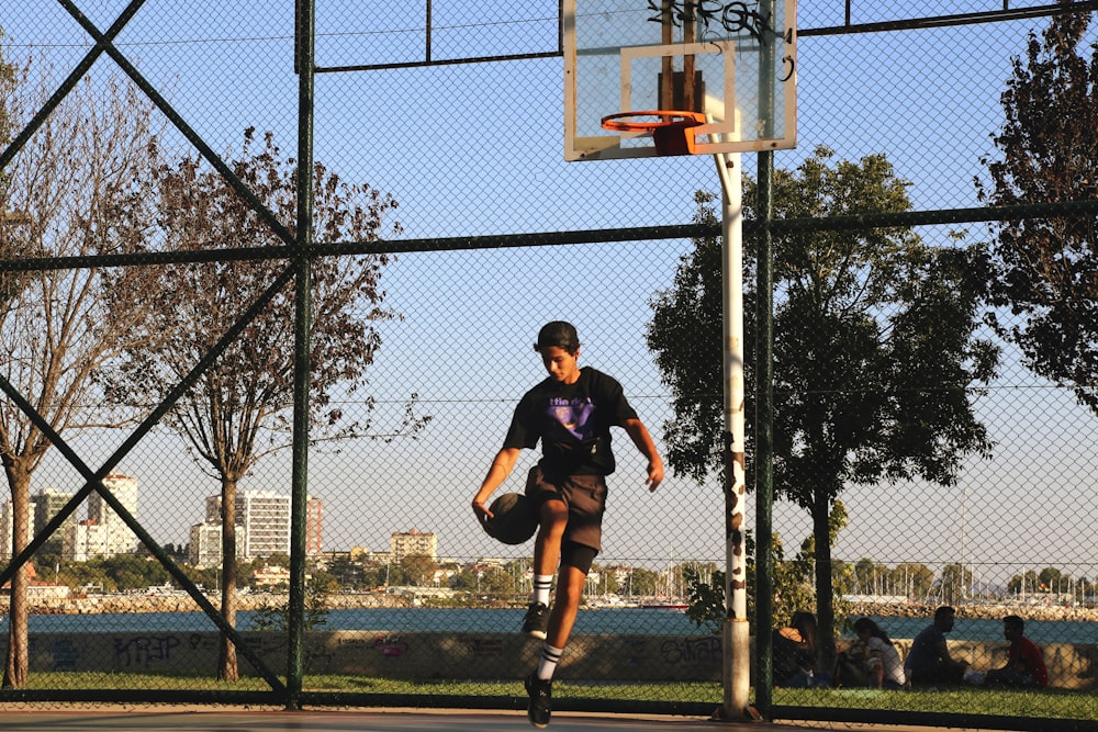 man in black shirt and black shorts jumping on basketball hoop
