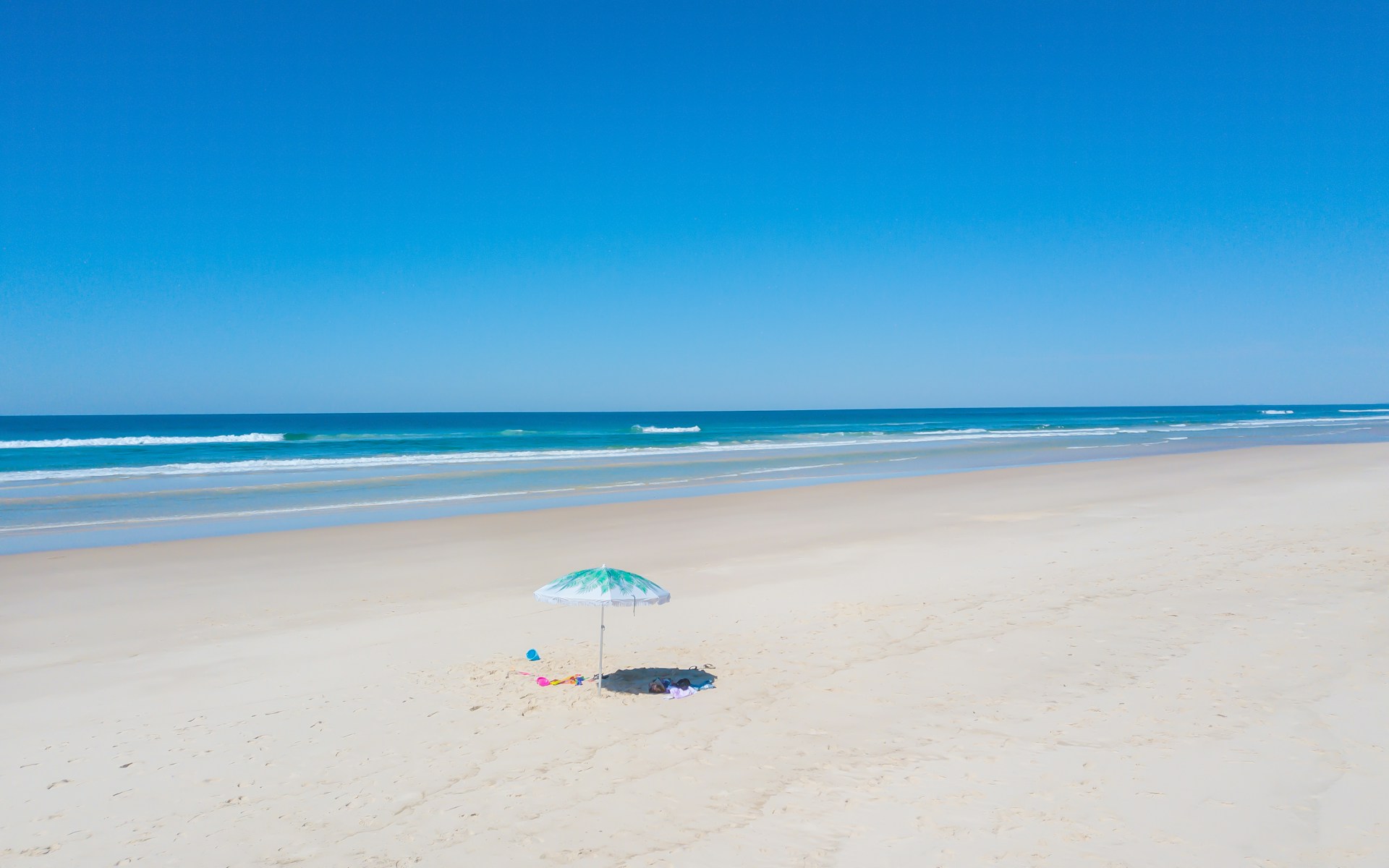 person holding white umbrella walking on beach during daytime