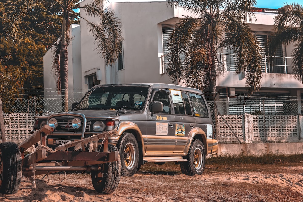 brown and black suv parked near white concrete building during daytime