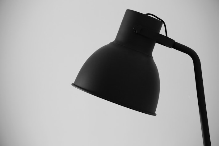 A sleek minimalist 3D printed lamp glowing softly on a modern desk setup