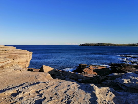 brown rock formation near body of water during daytime in Maroubra NSW Australia