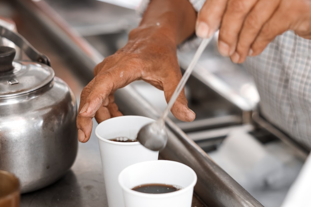 person pouring water on white ceramic mug