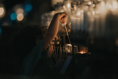 Children lighting candles inside a humble church, surrounded by simple wooden pews.