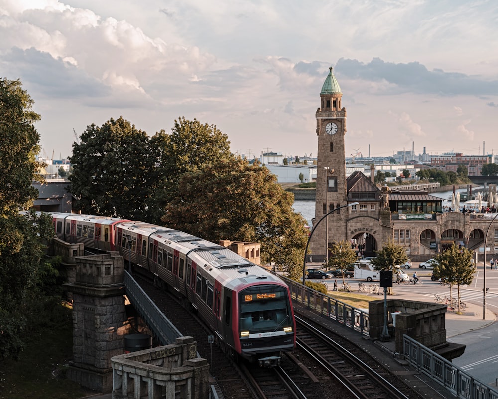 Brauner und weißer Zug tagsüber auf der Bahnstrecke in der Nähe des braunen Betongebäudes