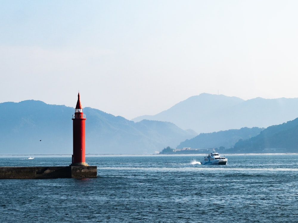 rot-weißer Leuchtturm in der Nähe des Gewässers tagsüber