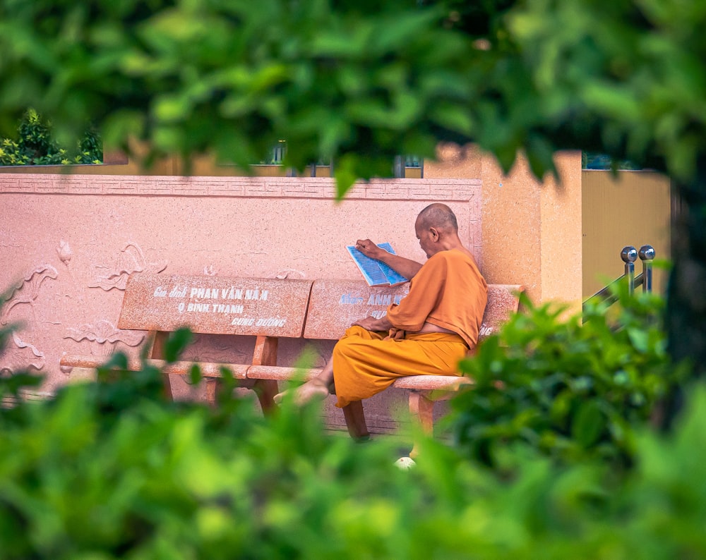 woman in orange long sleeve shirt sitting on brown wooden bench