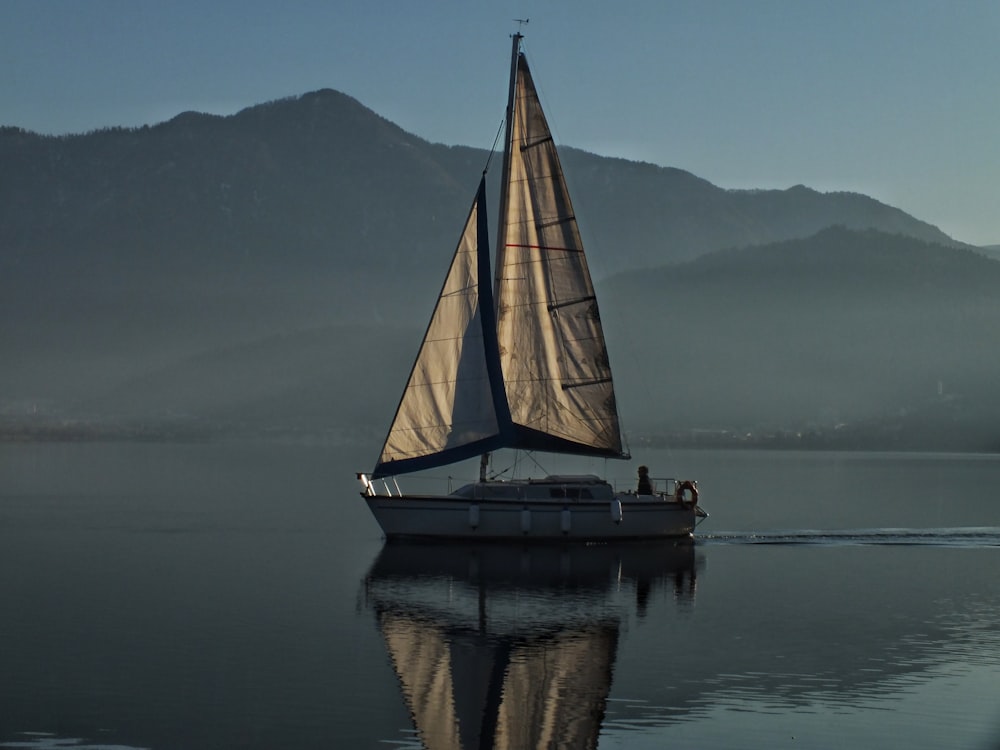 sailboat on calm water near mountain during daytime