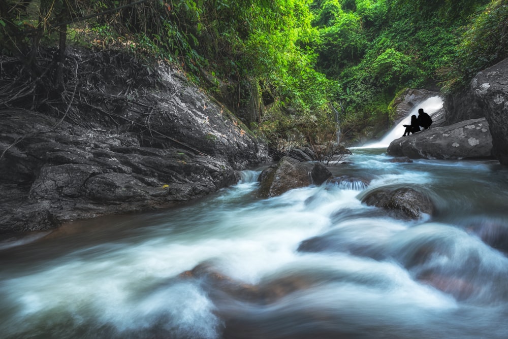 a man sitting on a rock in the middle of a river