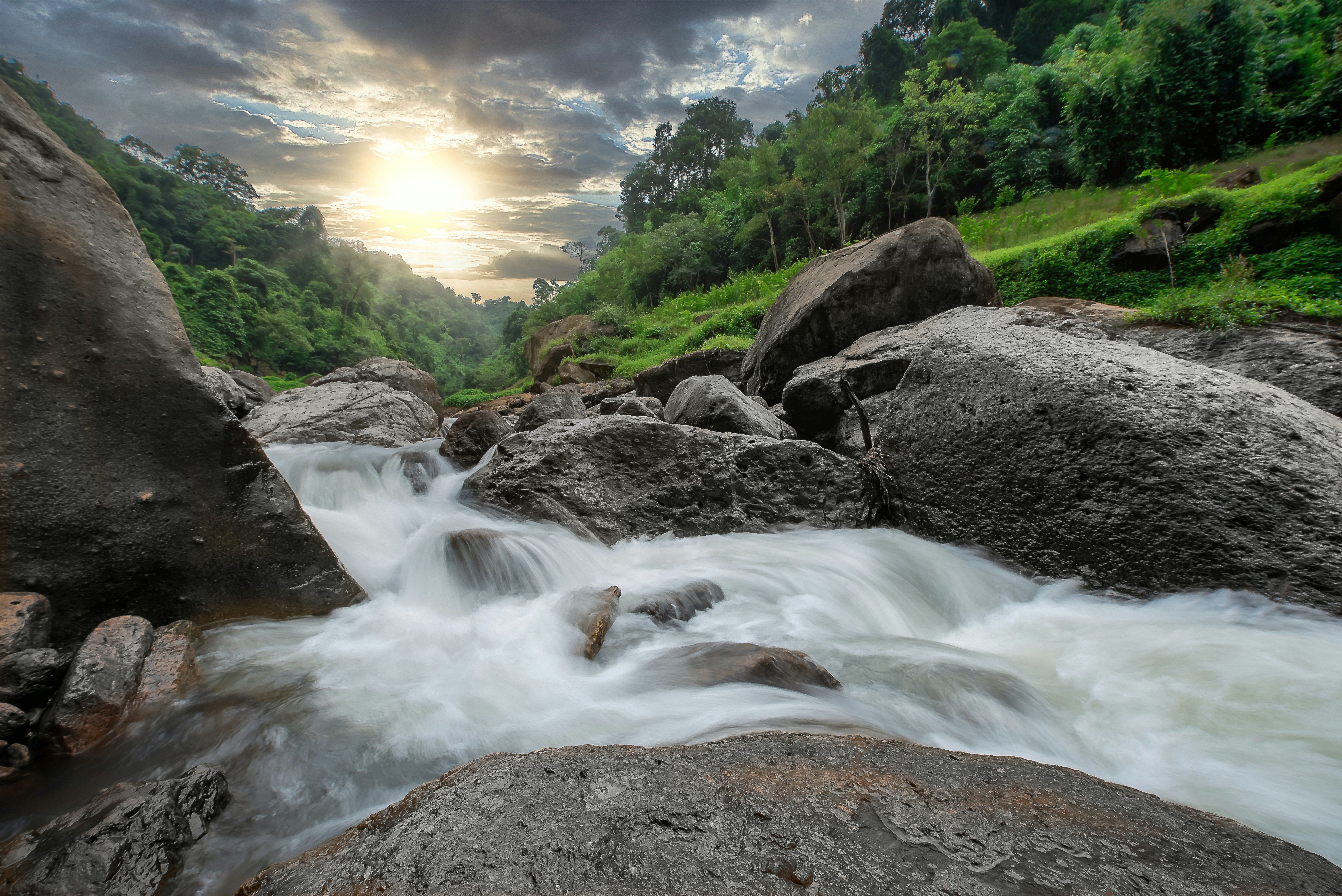 time lapse photography of river between green trees during daytime