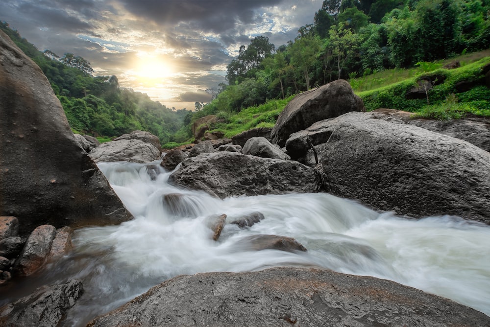 time lapse photography of river between green trees during daytime