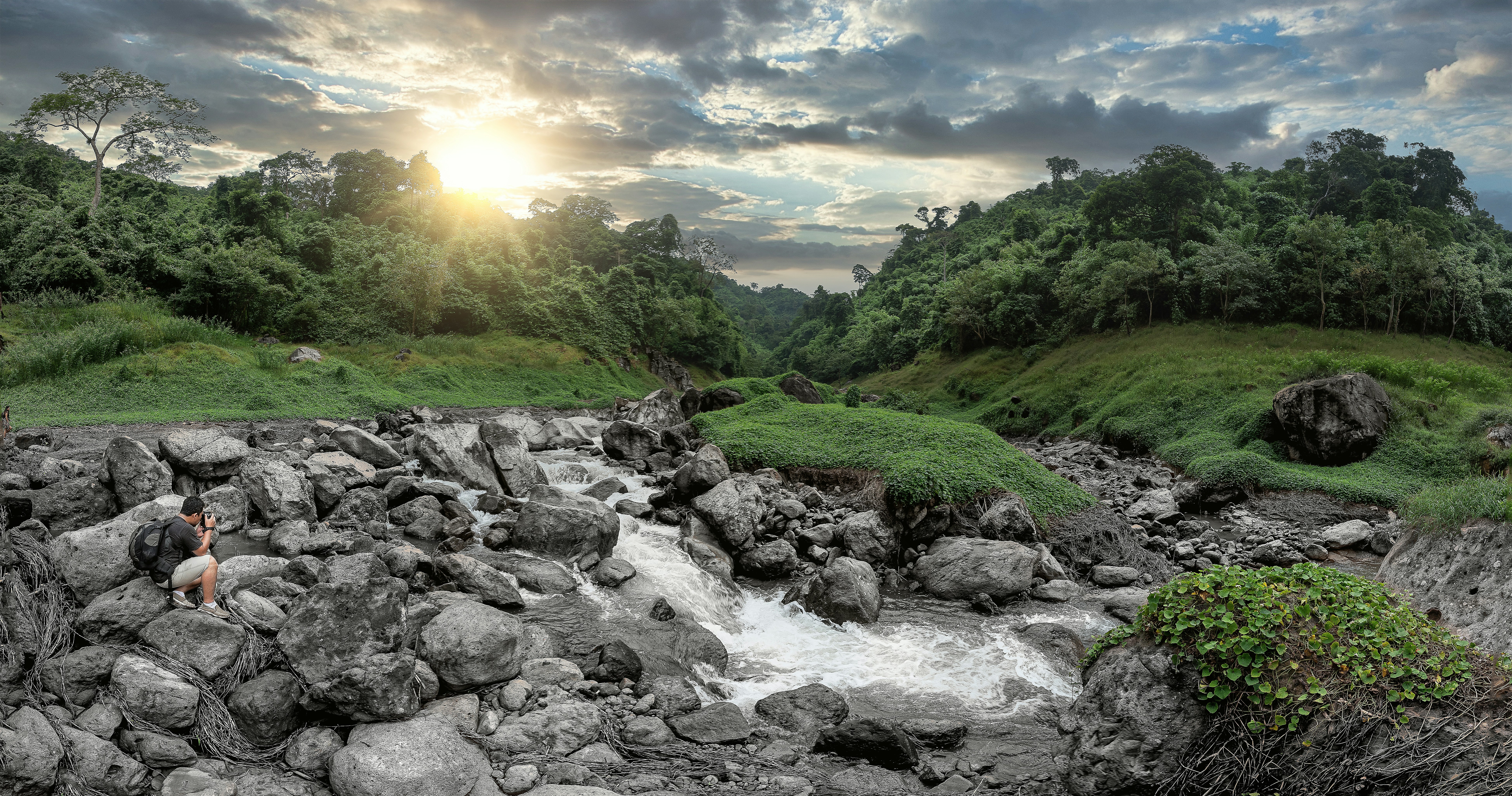 rocky river with rocks and green grass under blue sky and white clouds during daytime
