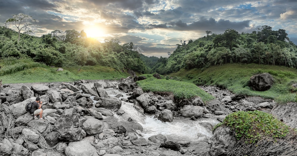 rocky river with rocks and green grass under blue sky and white clouds during daytime