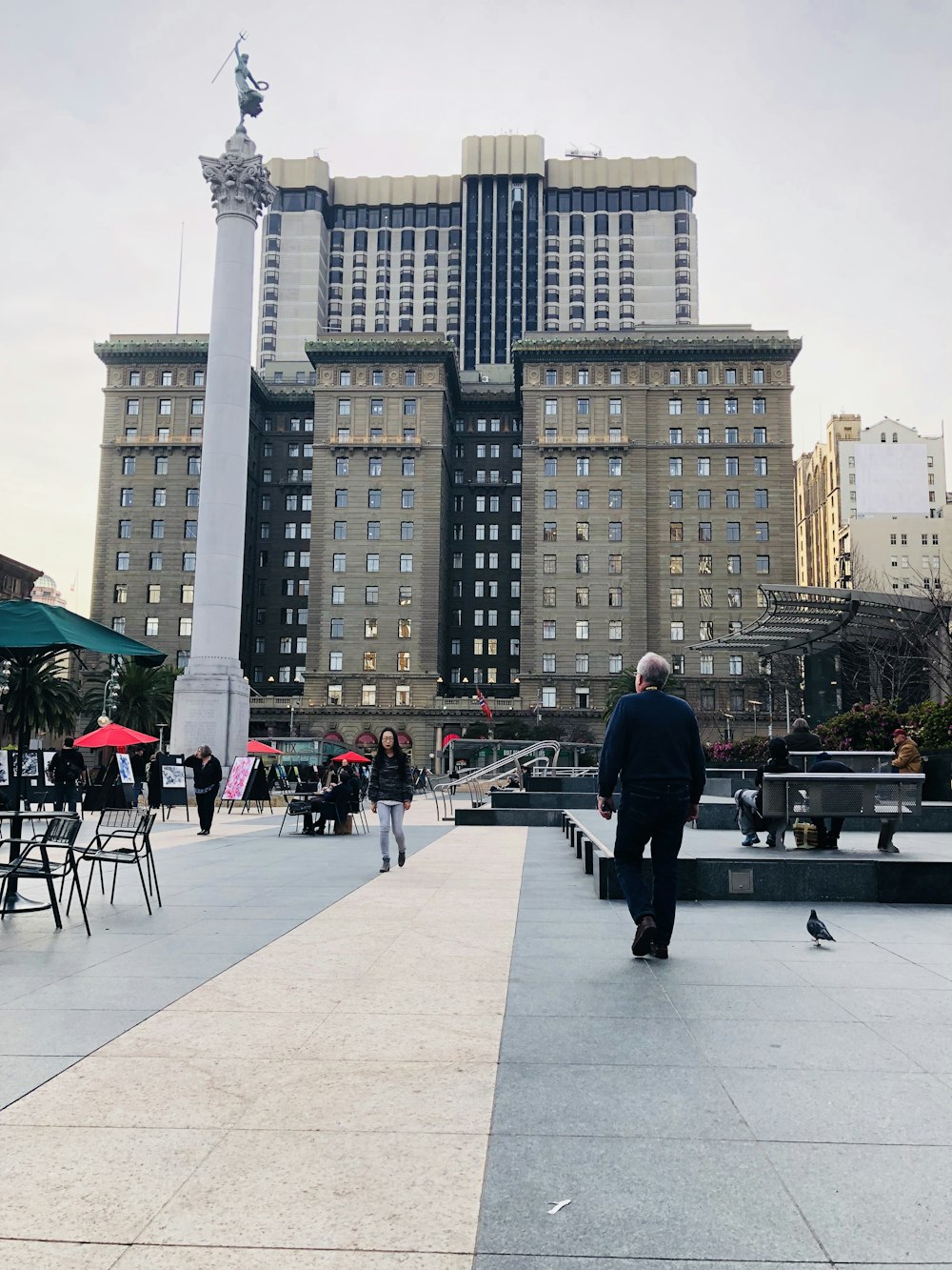 Hombre con chaqueta negra de pie sobre el piso de concreto gris durante el día