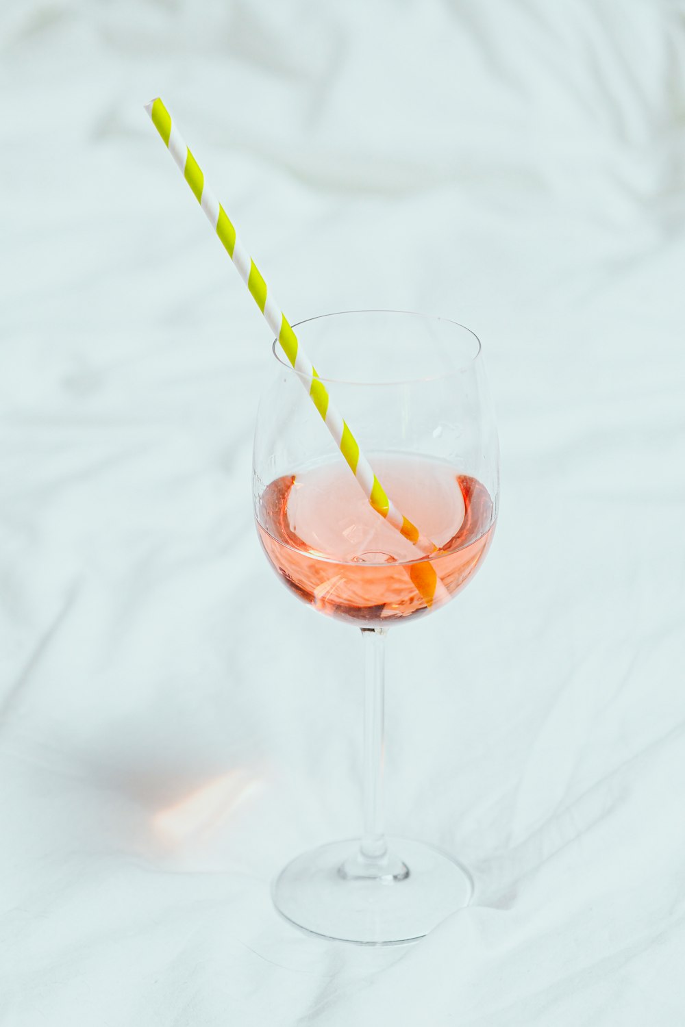 clear drinking glass with orange liquid and green straw