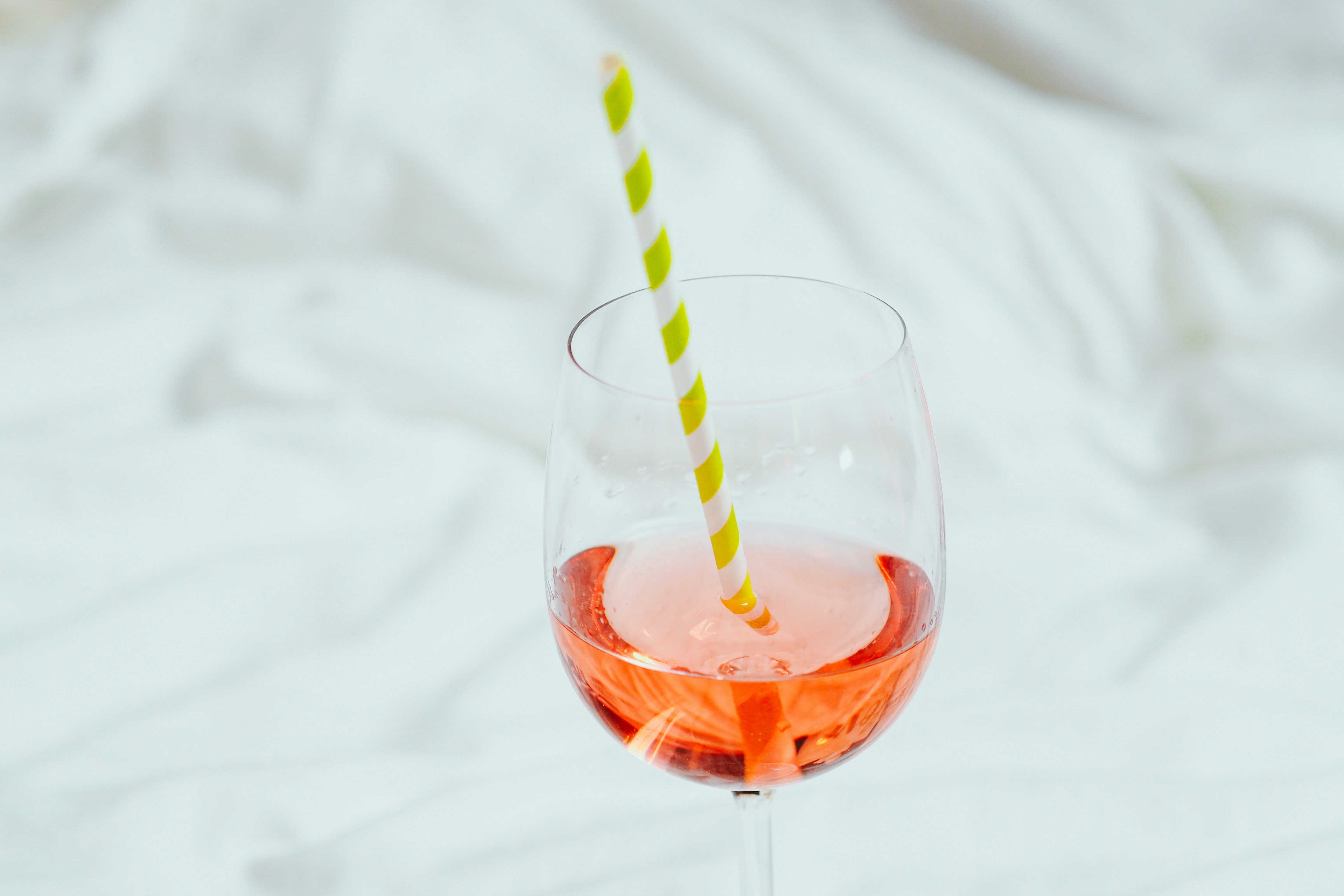 clear drinking glass with orange liquid and green straw