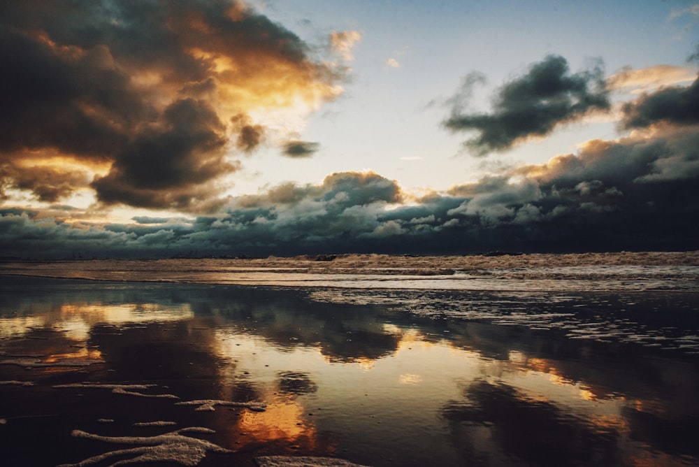 body of water under cloudy sky during sunset