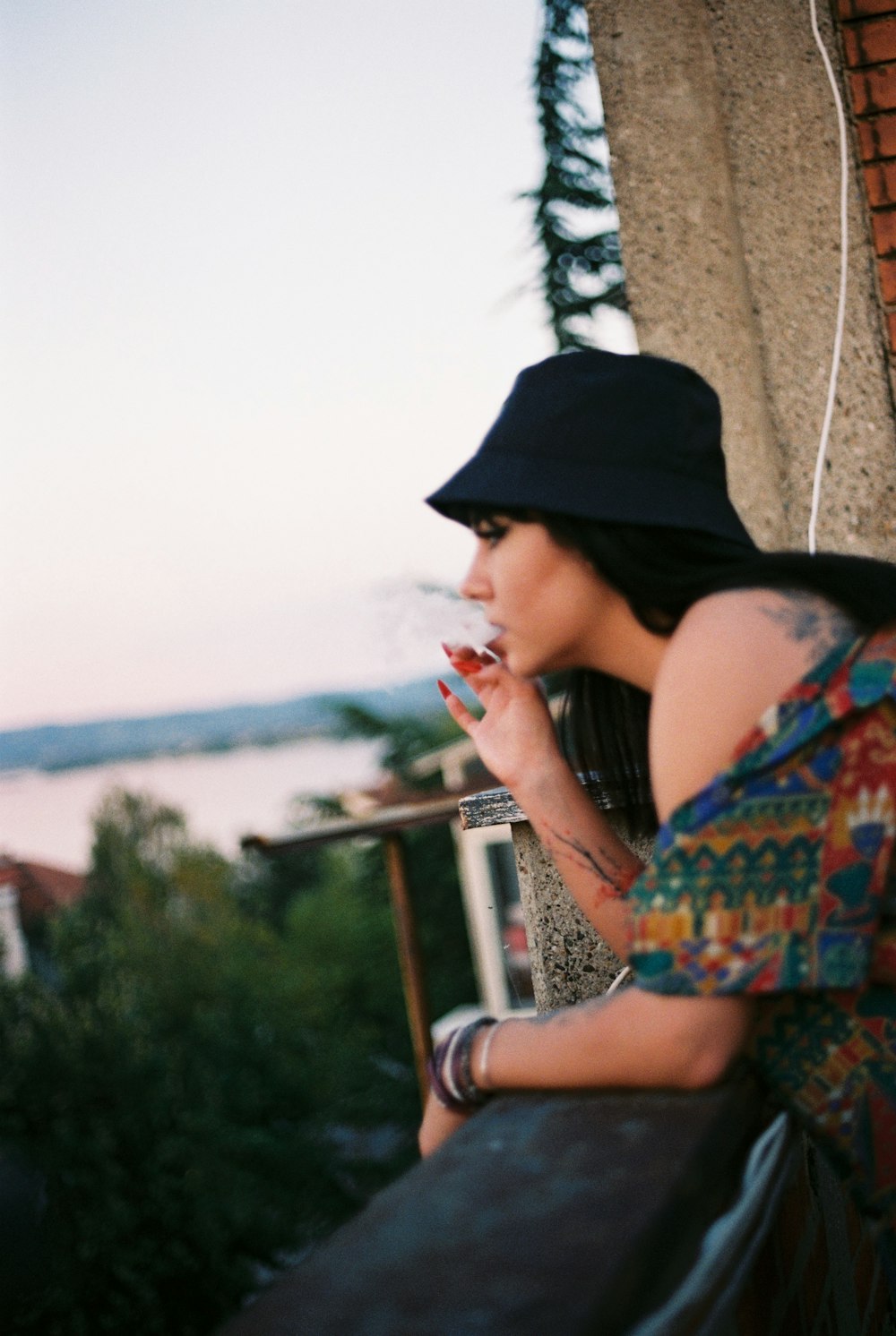 woman in black cap and red and green floral dress