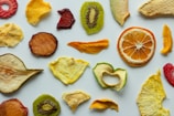 Assorted freeze-dried fruit medley in vibrant colors spread out on a white surface.