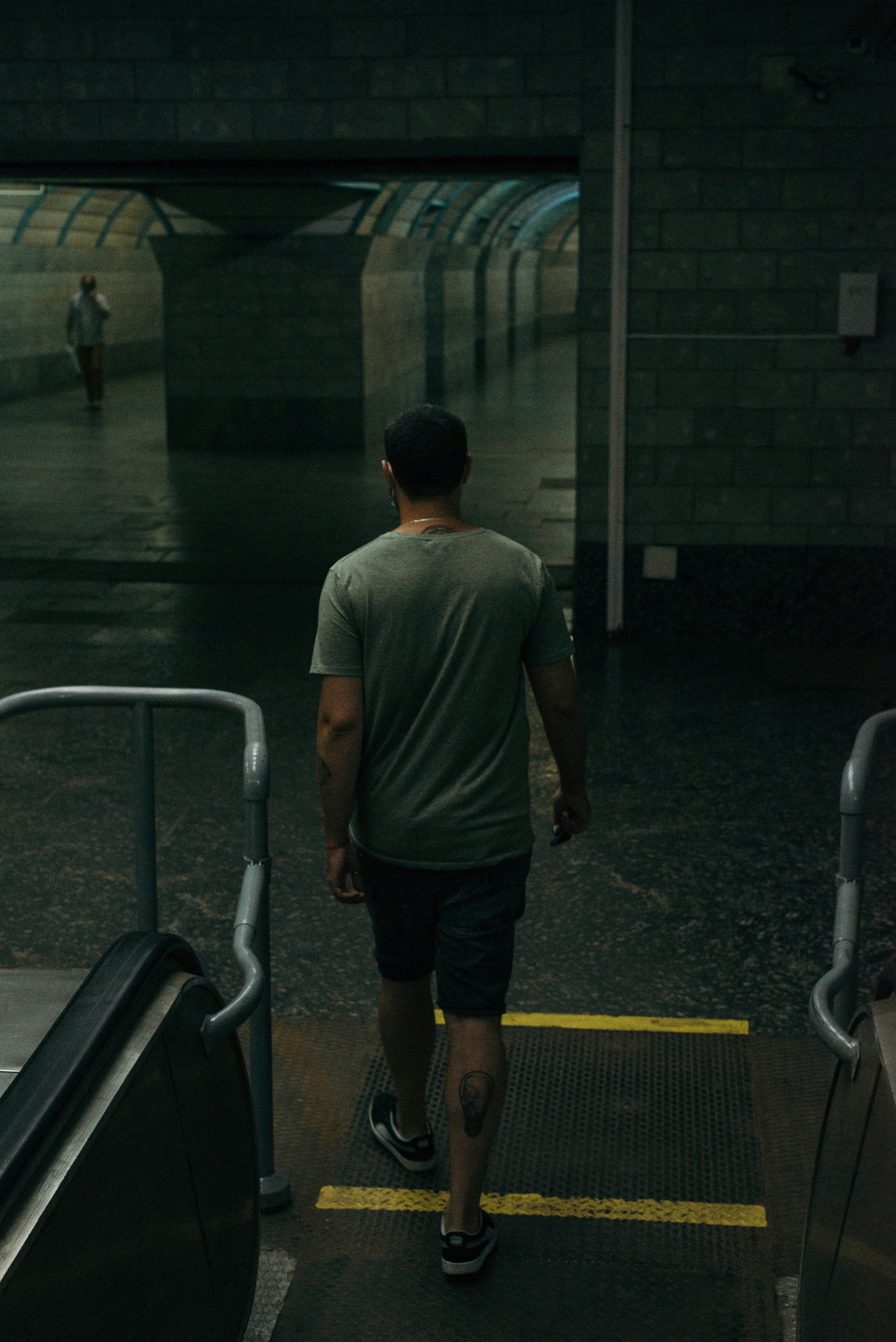 廊下を歩く灰色のTシャツと黒の短パンの男