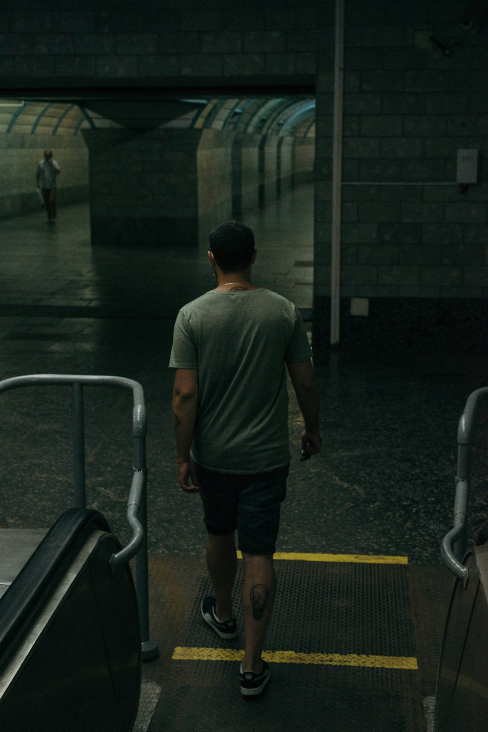 Hombre con camiseta gris y pantalones cortos negros caminando por el pasillo
