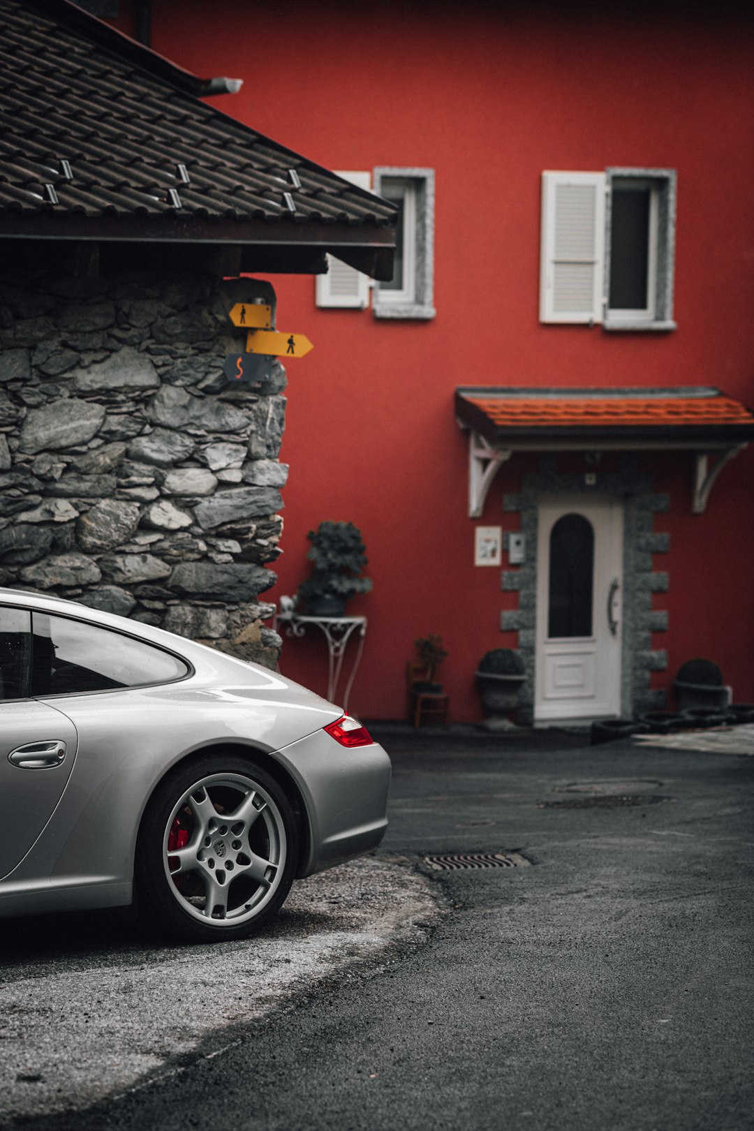white porsche 911 parked beside red and white concrete building during daytime