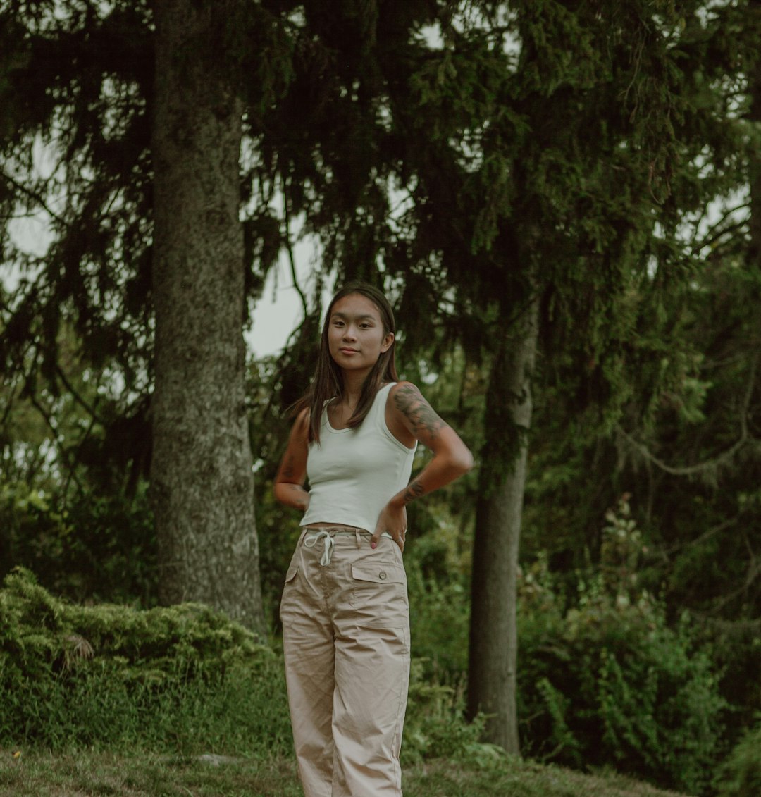 woman in white tank top and beige pants standing on green grass field