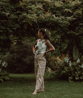 A smiling person embracing nature, standing barefoot on grass.