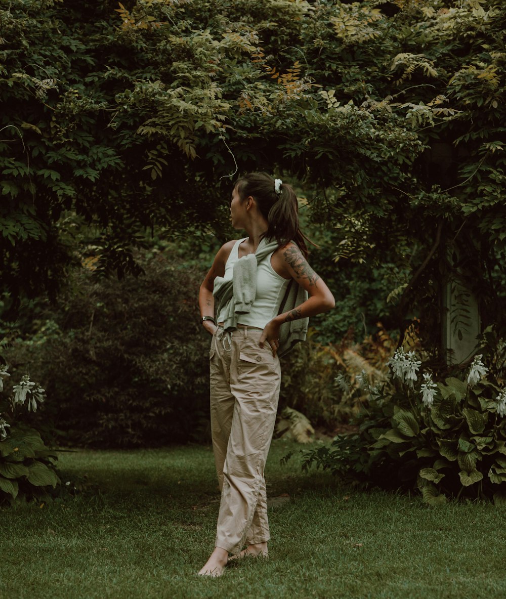 woman in green and white stripe tank top and brown pants standing on green grass field