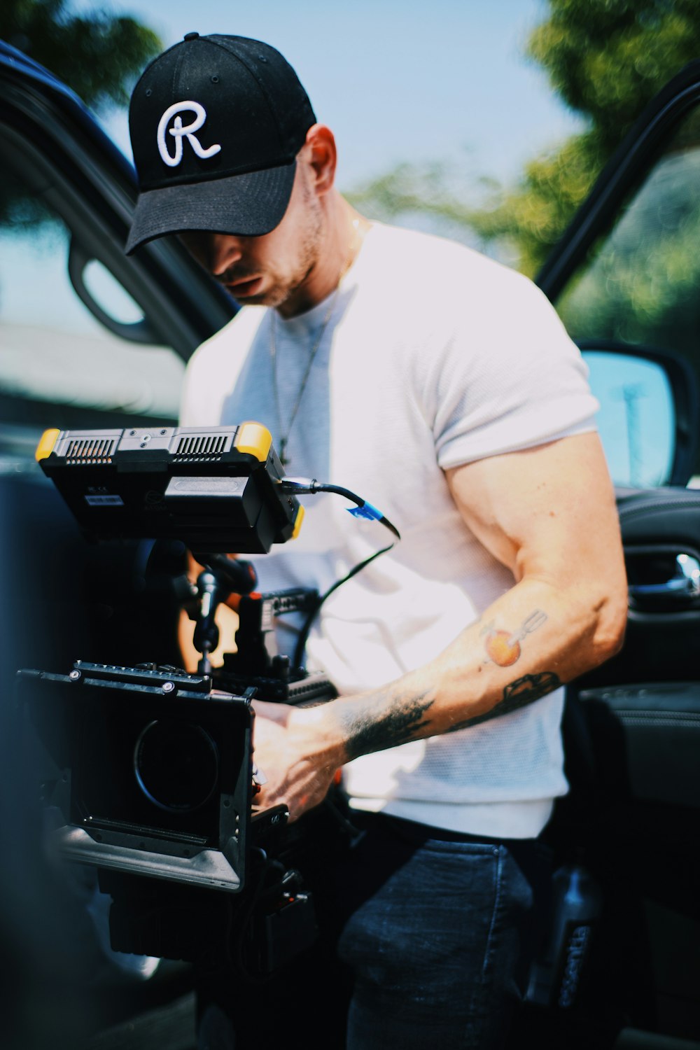 man in white t-shirt holding black video camera