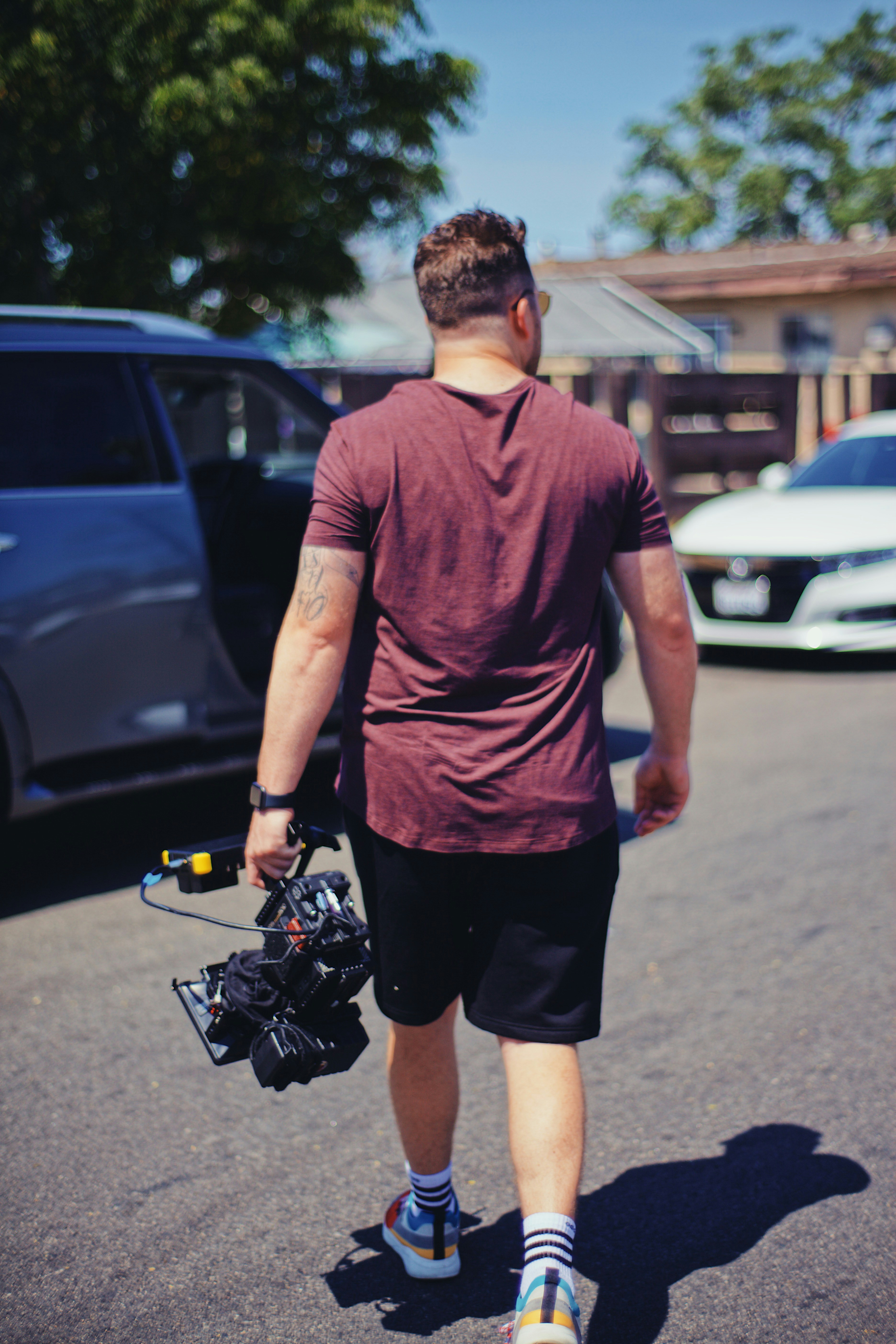 man in purple crew neck t-shirt and black shorts standing on gray concrete pavement during