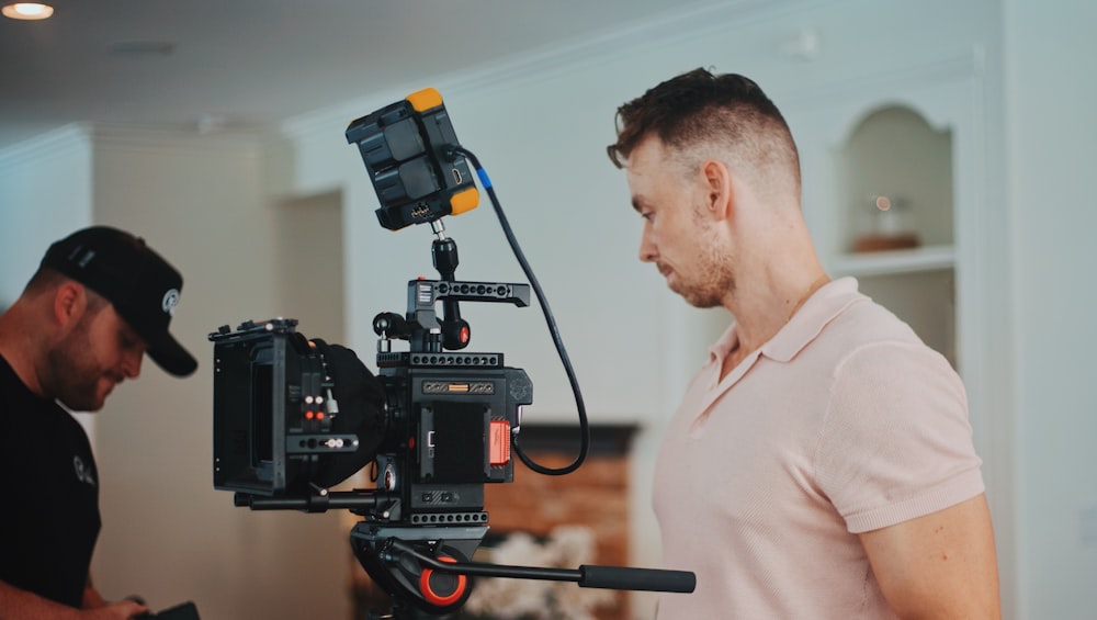 man in white dress shirt holding black video camera