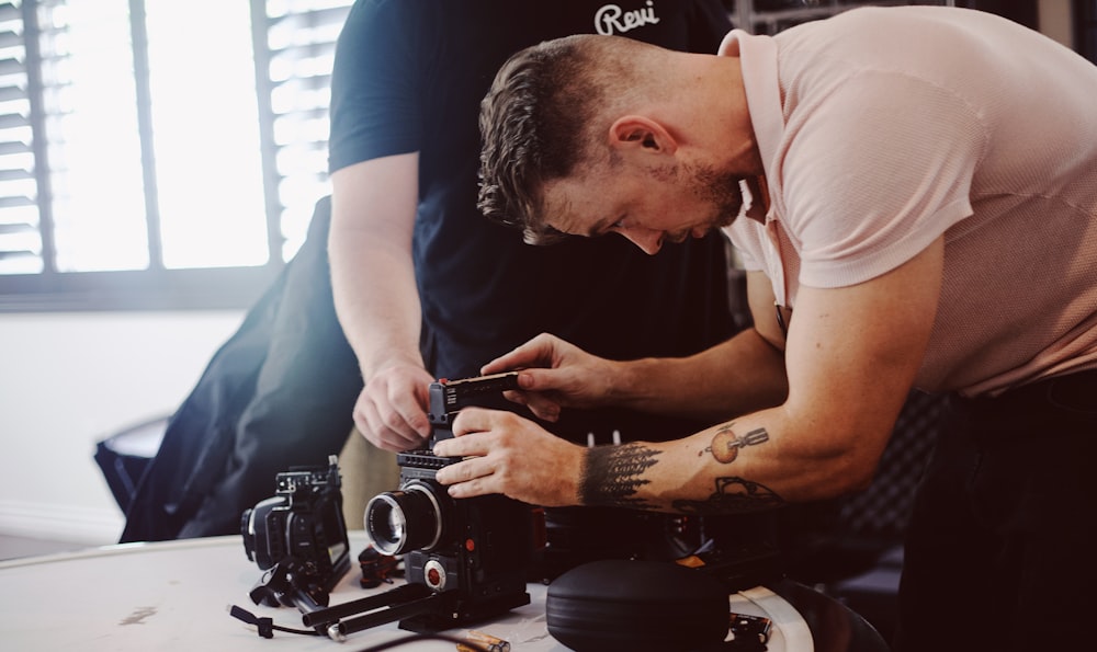 man in white t-shirt holding black camera