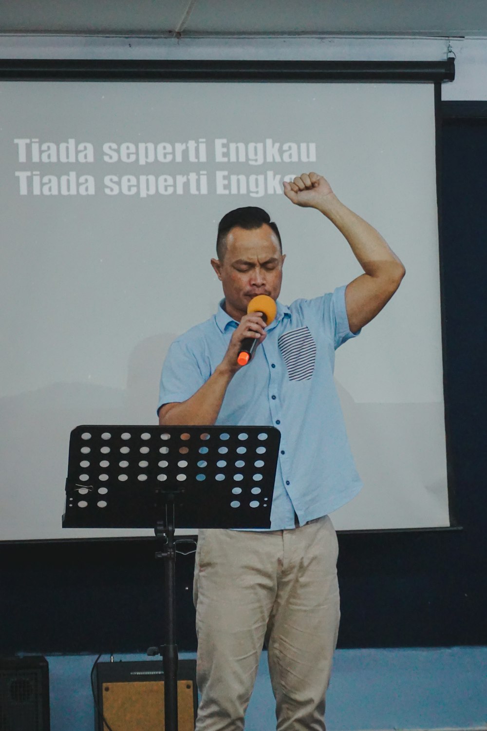 man in white button up shirt and brown pants holding microphone