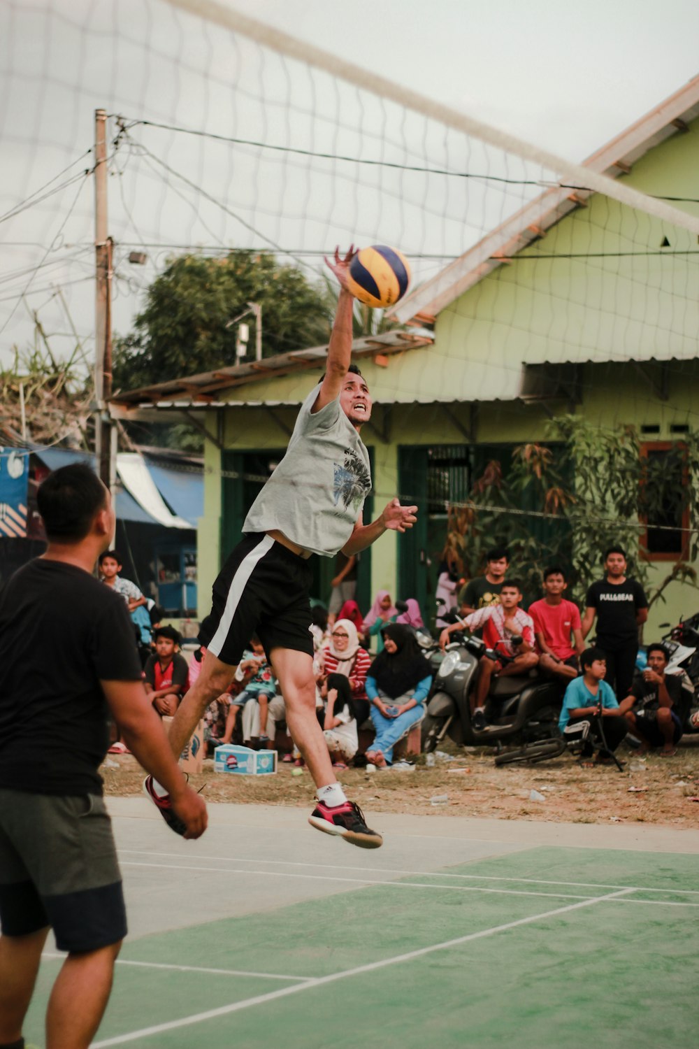 homem de camiseta branca de pescoço de tripulação e calção preto segurando voleibol amarelo