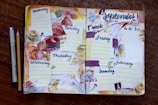 A hand-crafted planner spread for the first week of September 2020, featuring a floral and autumn theme. Each day of the week is sectioned off with colorful decorations, including pressed leaves, floral drawings, and textured paper strips. The layout is lively, with a variety of elements such as dotted lines for daily entries, a 'to do list' on the right page, and artistic embellishments like stamps and watercolor effects. A pen and pencil are placed beside the planner on a wooden surface.