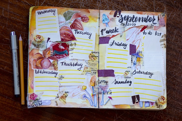 A hand-crafted planner spread for the first week of September 2020, featuring a floral and autumn theme. Each day of the week is sectioned off with colorful decorations, including pressed leaves, floral drawings, and textured paper strips. The layout is lively, with a variety of elements such as dotted lines for daily entries, a 'to do list' on the right page, and artistic embellishments like stamps and watercolor effects. A pen and pencil are placed beside the planner on a wooden surface.