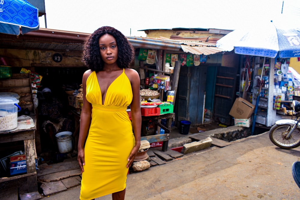 woman in yellow tank top and yellow skirt standing on sidewalk during daytime