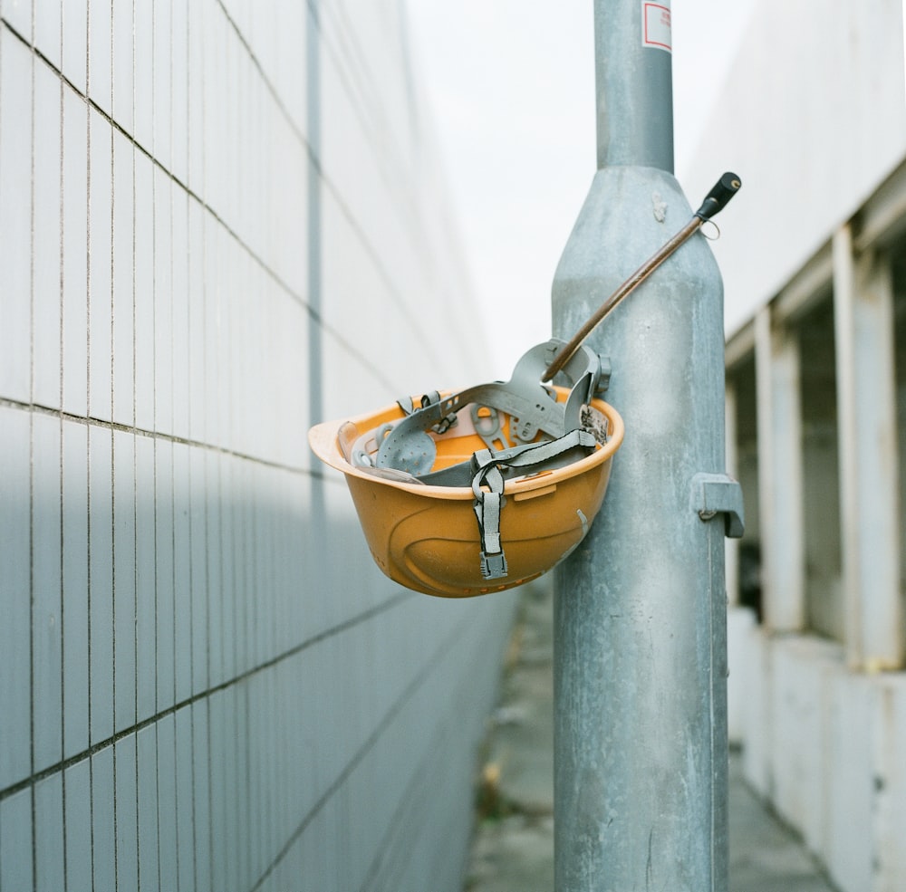 orange and gray backpack hanging on gray metal pipe