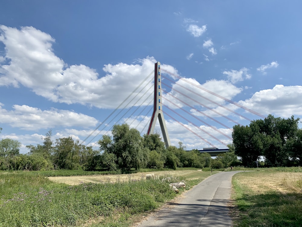 Graue Betonstraße zwischen grünem Grasfeld unter blauem Himmel und weißen Wolken tagsüber