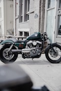blue and black standard motorcycle parked beside brown concrete building during daytime
