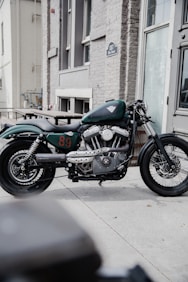 blue and black standard motorcycle parked beside brown concrete building during daytime