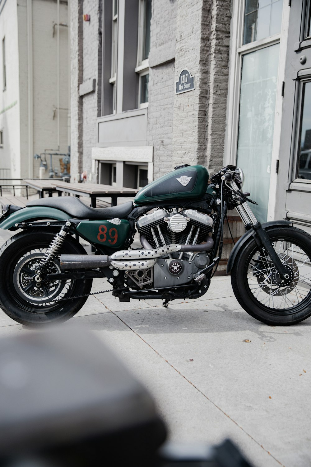 Motocicleta estándar azul y negra estacionada al lado de un edificio de concreto marrón durante el día