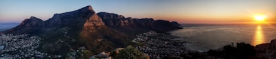 A panoramic view of Cape Town's coastline with Table Mountain in the background during sunset.