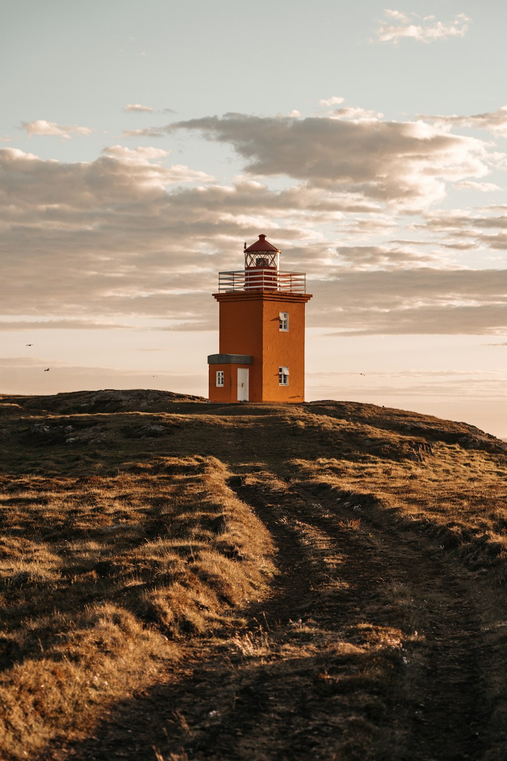 brown and white lighthouse on brown field under cloudy sky during daytime