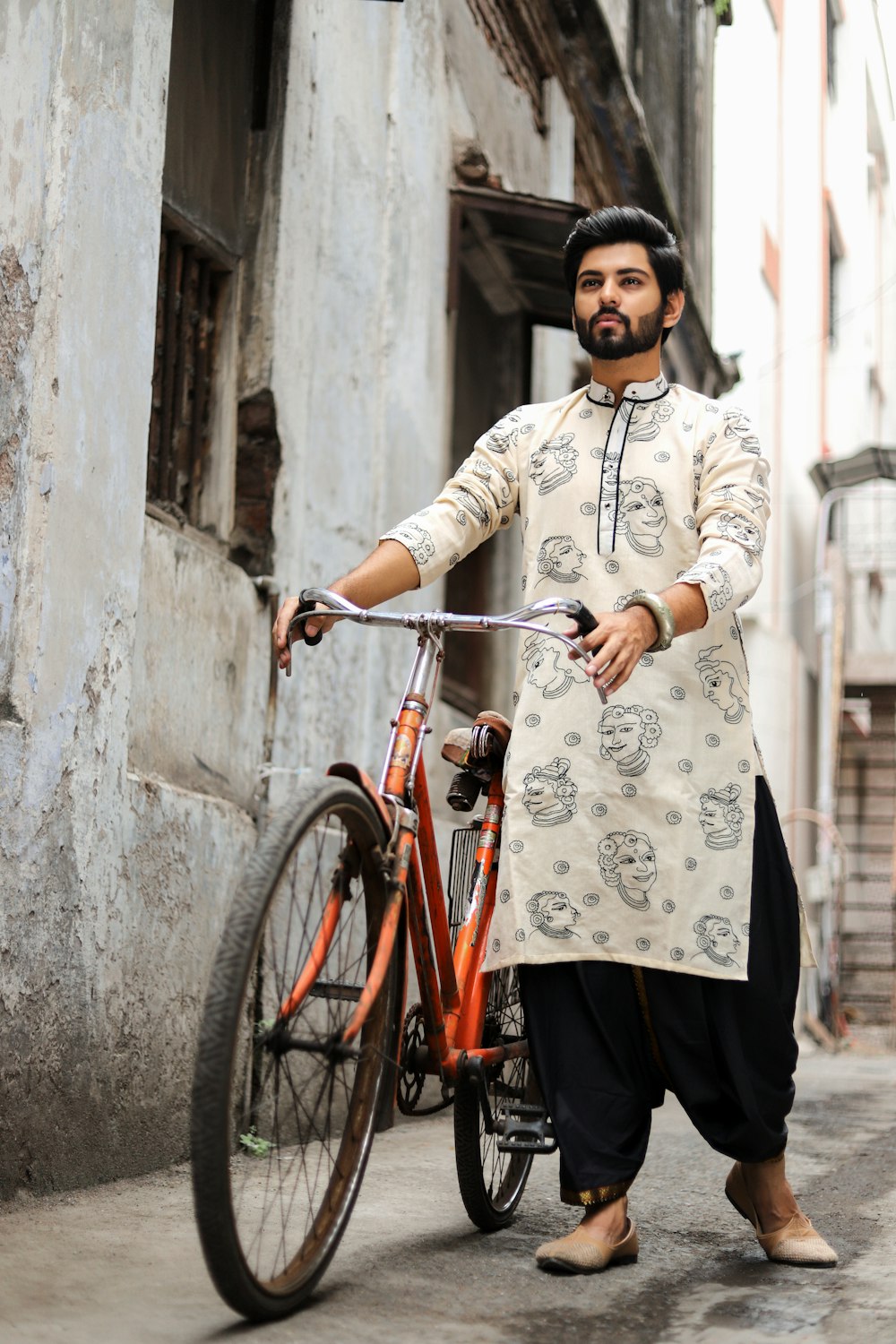 woman in white and black floral long sleeve dress and black pants standing beside red bicycle