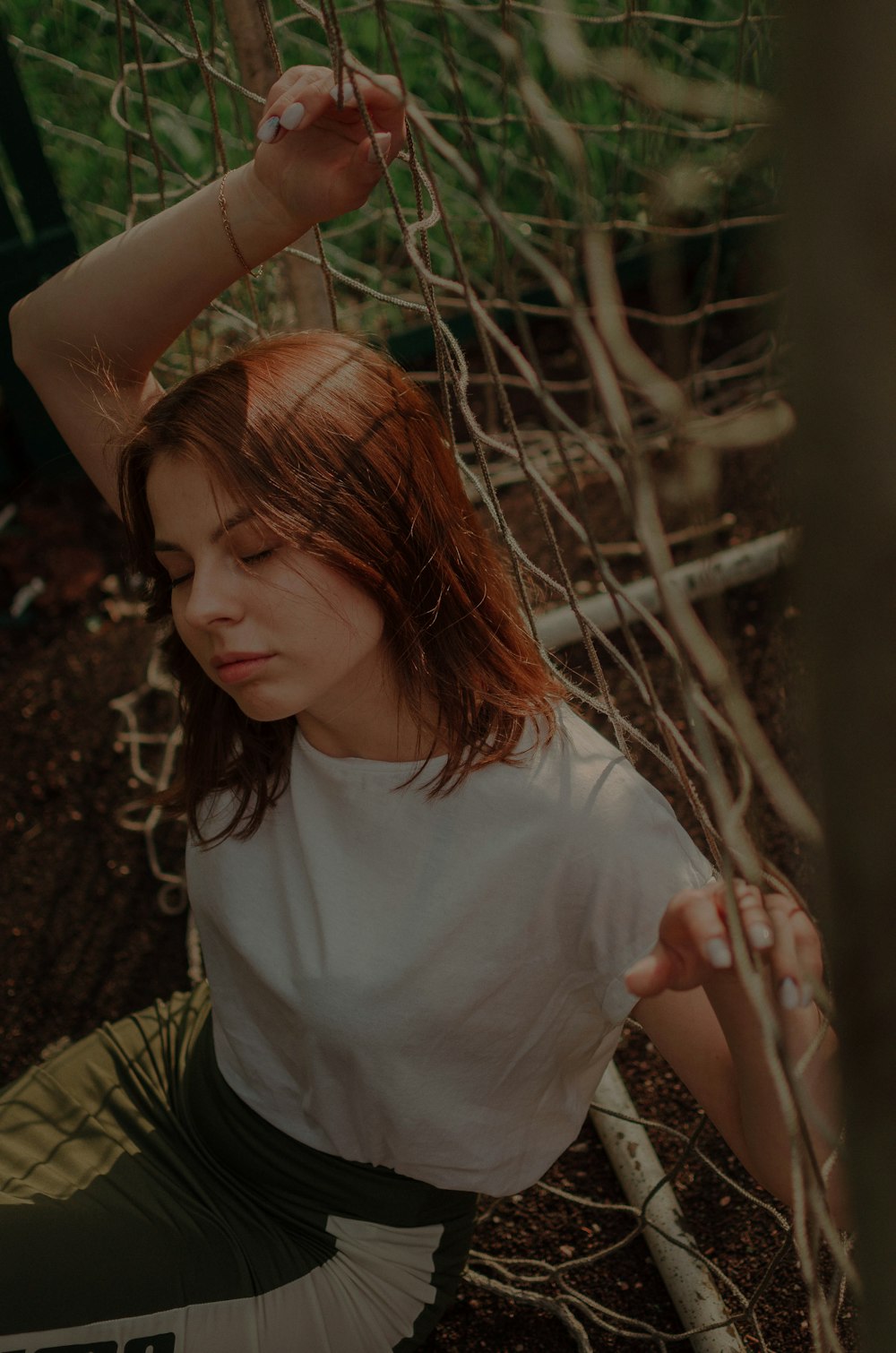 woman in white shirt holding brown tree branch