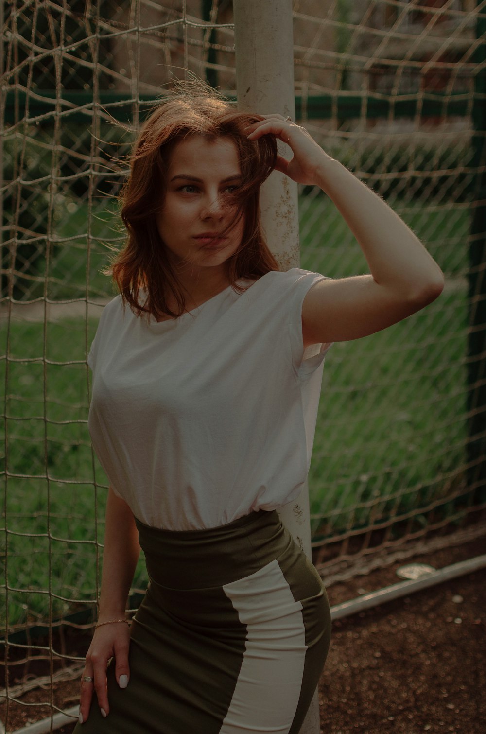 woman in white t-shirt and black shorts standing near fence during daytime